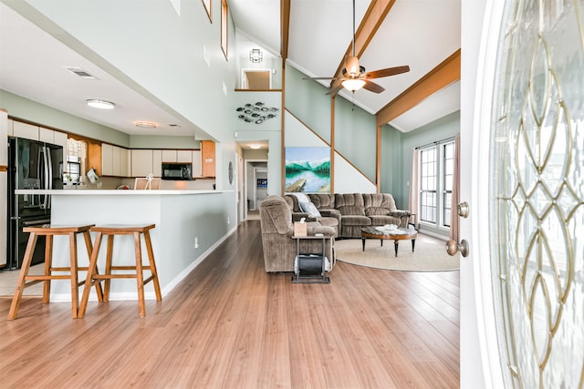 living room featuring ceiling fan, high vaulted ceiling, and light hardwood / wood-style flooring