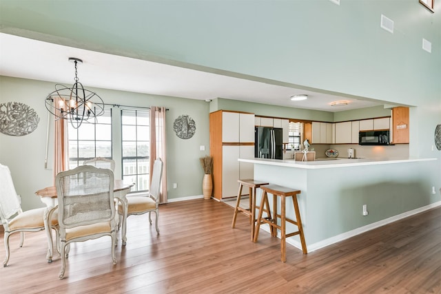 kitchen featuring black appliances, light hardwood / wood-style floors, white cabinetry, and kitchen peninsula