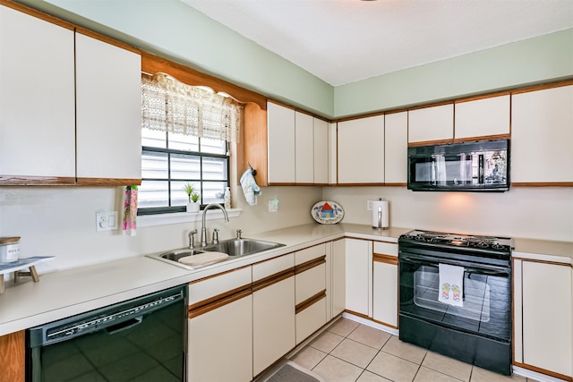 kitchen with white cabinets, sink, light tile patterned flooring, and black appliances