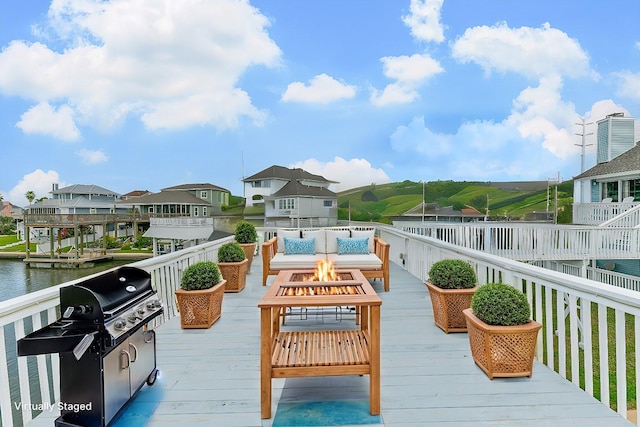 wooden deck with a water view and an outdoor living space with a fire pit