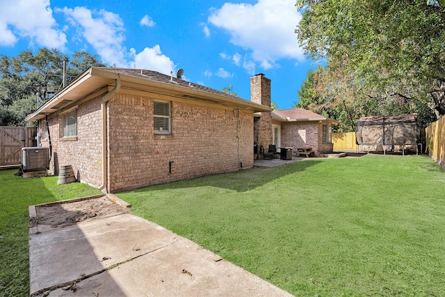 rear view of property with a yard, a trampoline, and a patio