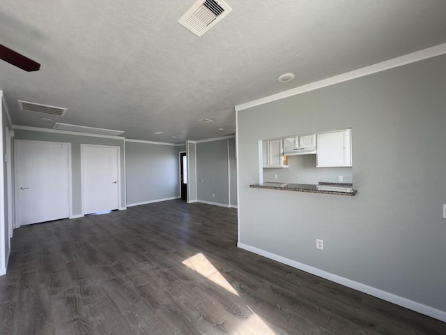 unfurnished living room with dark hardwood / wood-style flooring, ornamental molding, and a textured ceiling