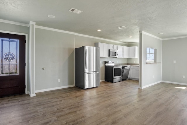 kitchen featuring visible vents, baseboards, appliances with stainless steel finishes, wood finished floors, and white cabinetry