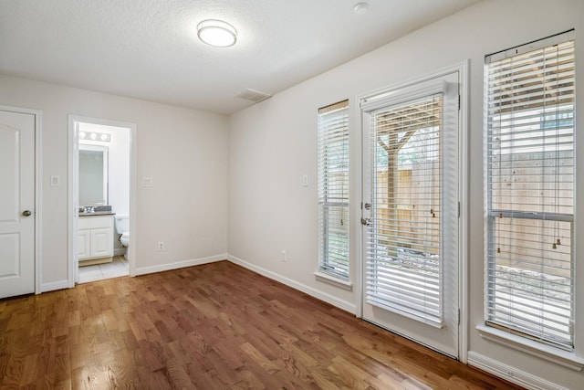 interior space with connected bathroom, access to exterior, hardwood / wood-style floors, and a textured ceiling