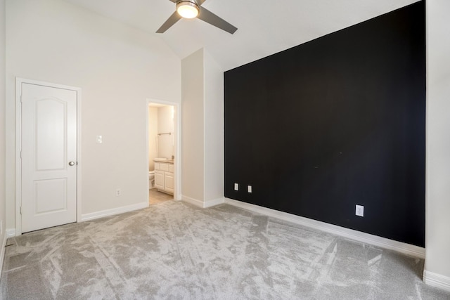 unfurnished bedroom with ceiling fan, light colored carpet, ensuite bathroom, and high vaulted ceiling