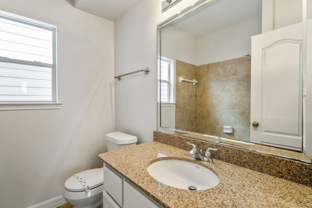 bathroom featuring vanity, a tile shower, and toilet