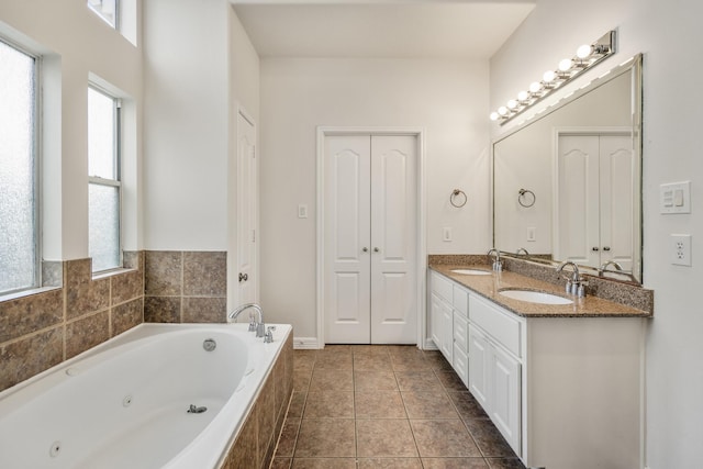 bathroom featuring tile patterned flooring, vanity, and tiled bath