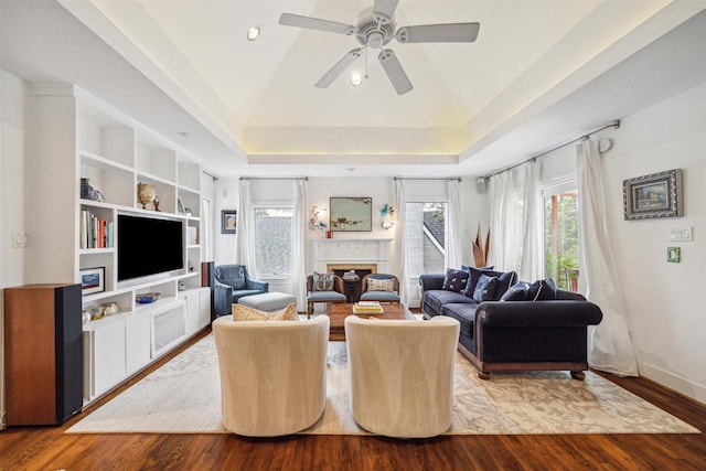 living room with hardwood / wood-style flooring, ceiling fan, a raised ceiling, and lofted ceiling