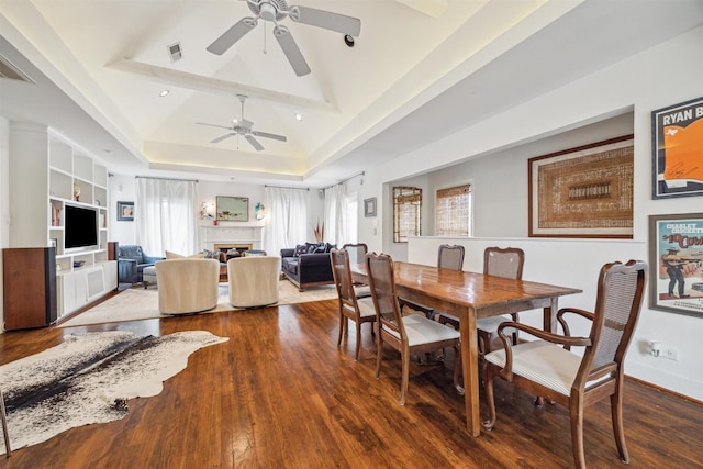 dining space featuring wood-type flooring, a raised ceiling, built in features, and plenty of natural light