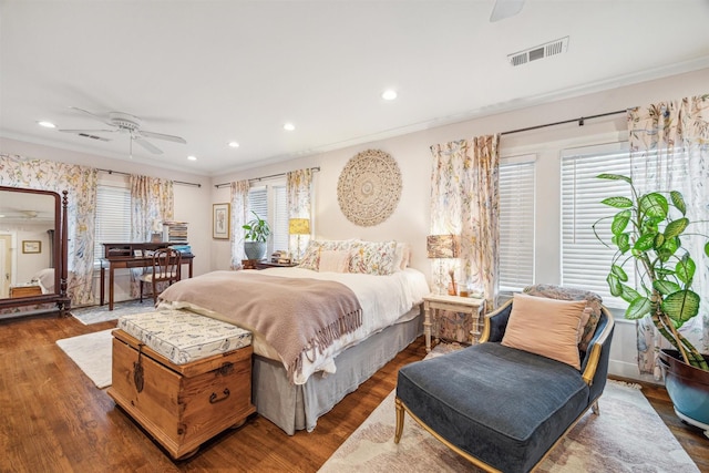 bedroom with dark hardwood / wood-style flooring, ceiling fan, and crown molding