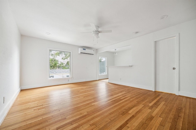 unfurnished room featuring light wood-type flooring, a wall mounted AC, and ceiling fan