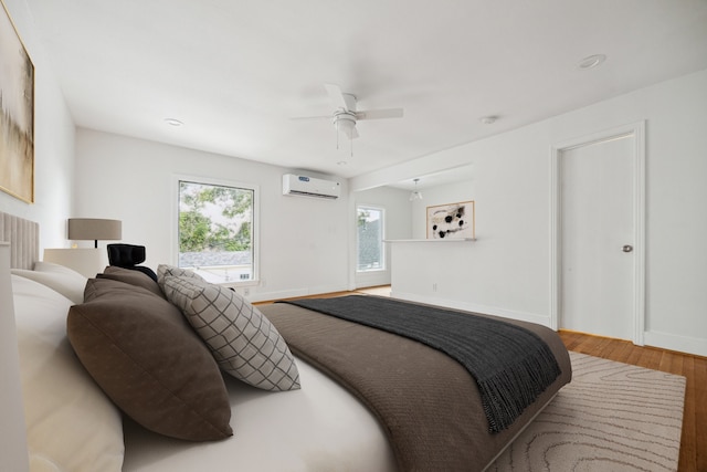 bedroom with wood-type flooring, an AC wall unit, and ceiling fan