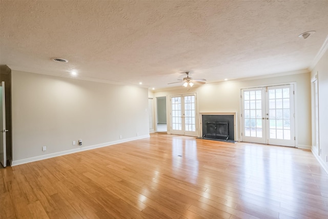 unfurnished living room featuring french doors, light hardwood / wood-style floors, a textured ceiling, and ornamental molding