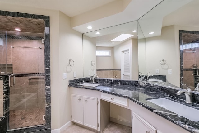 bathroom featuring tile patterned floors, vanity, a shower with shower door, and a skylight