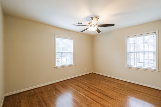 empty room with hardwood / wood-style floors, ceiling fan, and a healthy amount of sunlight