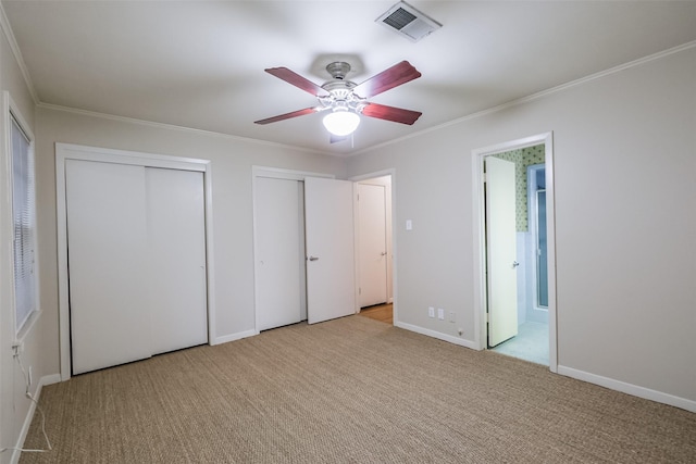 unfurnished bedroom featuring light carpet, ensuite bath, ceiling fan, and multiple closets