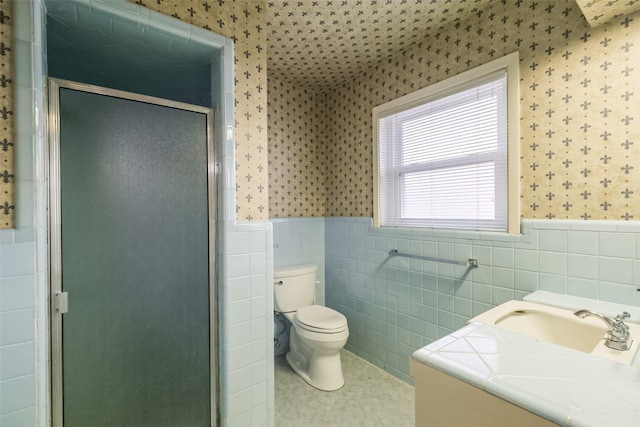 bathroom with vanity, toilet, an enclosed shower, and tile walls