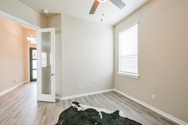 unfurnished room featuring french doors, light wood-type flooring, and ceiling fan