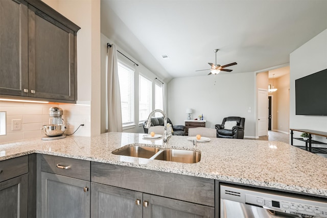 kitchen featuring sink, stainless steel dishwasher, ceiling fan, light stone countertops, and dark brown cabinetry