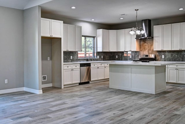 kitchen with wall chimney range hood, hanging light fixtures, white cabinets, and appliances with stainless steel finishes