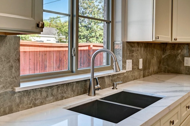 interior details with tasteful backsplash, sink, and light stone counters