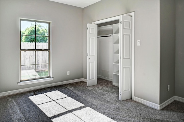 unfurnished bedroom with dark carpet and a closet