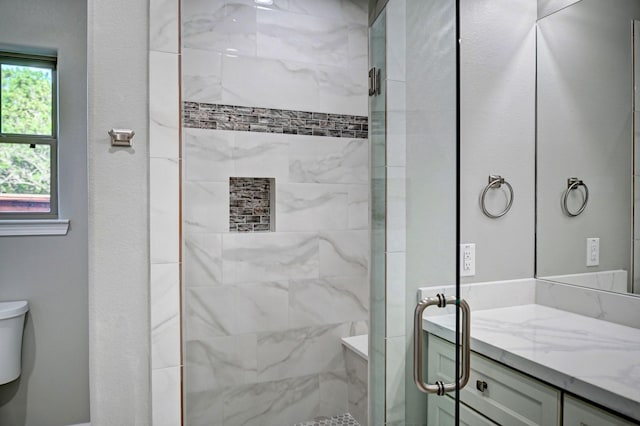 bathroom with a shower with door, vanity, and toilet