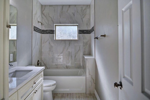 full bathroom with tiled shower / bath combo, vanity, hardwood / wood-style floors, and toilet