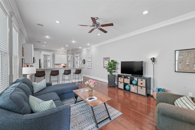 living room with a healthy amount of sunlight, wood-type flooring, and ornamental molding