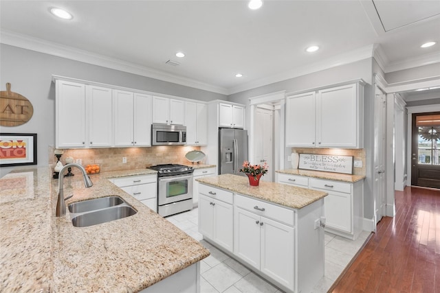 kitchen featuring light stone countertops, sink, stainless steel appliances, white cabinets, and light wood-type flooring