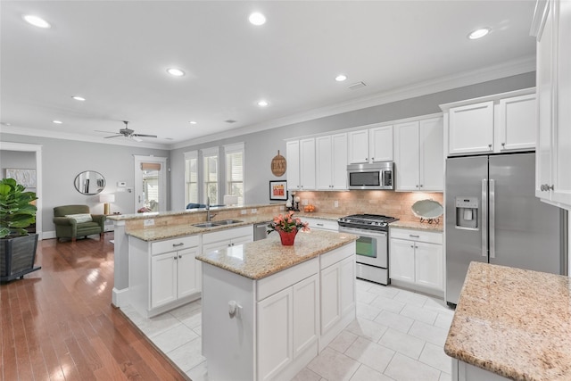 kitchen with kitchen peninsula, stainless steel appliances, white cabinetry, and sink