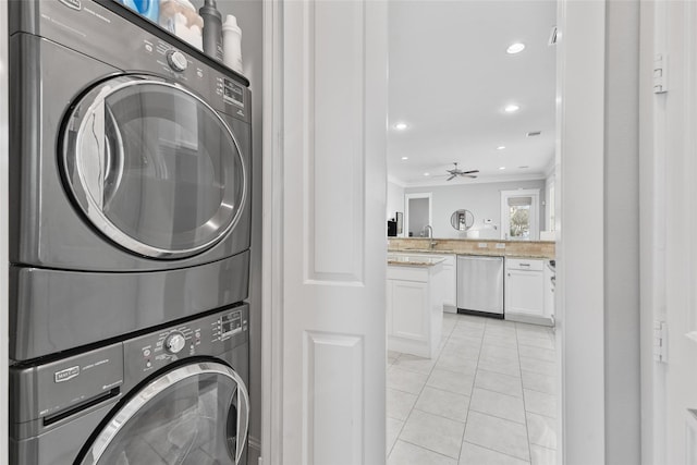 laundry room with crown molding, sink, ceiling fan, stacked washing maching and dryer, and light tile patterned floors