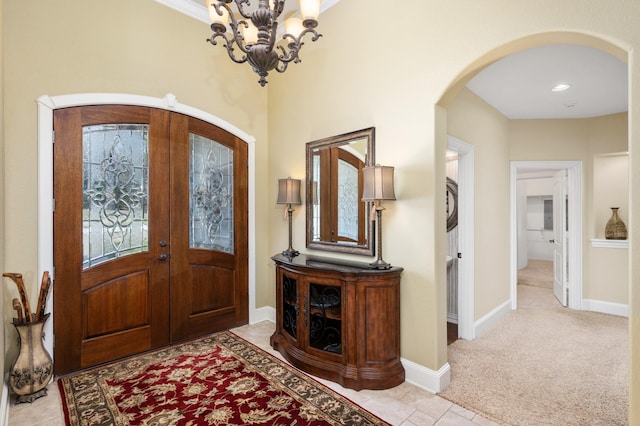 carpeted entryway with french doors, a chandelier, and ornamental molding