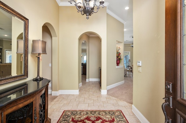 entrance foyer featuring ceiling fan with notable chandelier, light colored carpet, and crown molding