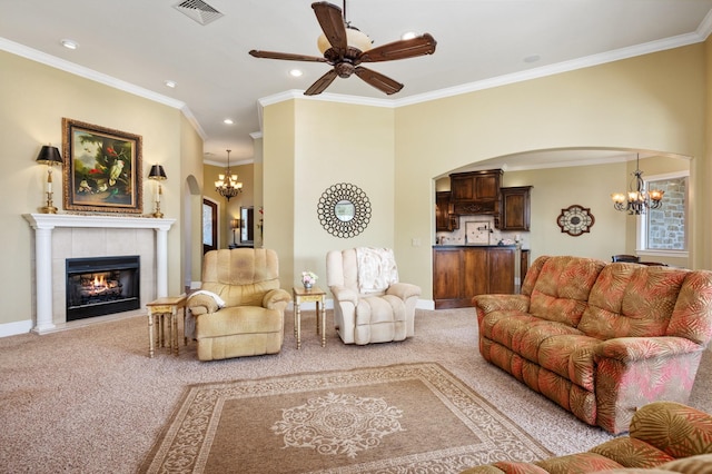 living room featuring a tiled fireplace, light carpet, ceiling fan with notable chandelier, and ornamental molding