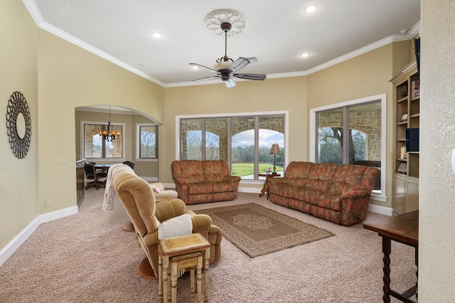 carpeted living room featuring ceiling fan with notable chandelier and ornamental molding