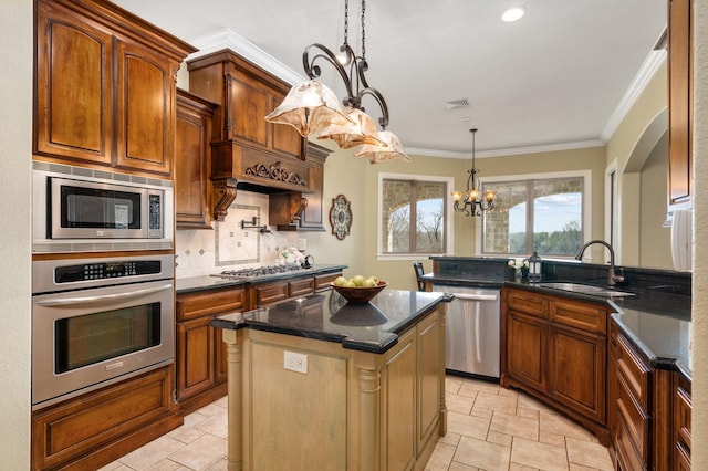 kitchen with sink, a chandelier, decorative light fixtures, a kitchen island, and appliances with stainless steel finishes