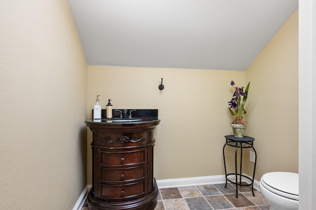 bathroom with vanity, vaulted ceiling, and toilet