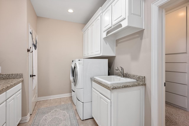 laundry room featuring cabinets, light tile patterned floors, washer and clothes dryer, and sink