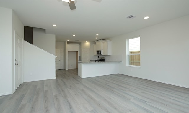 unfurnished living room featuring ceiling fan and light wood-type flooring