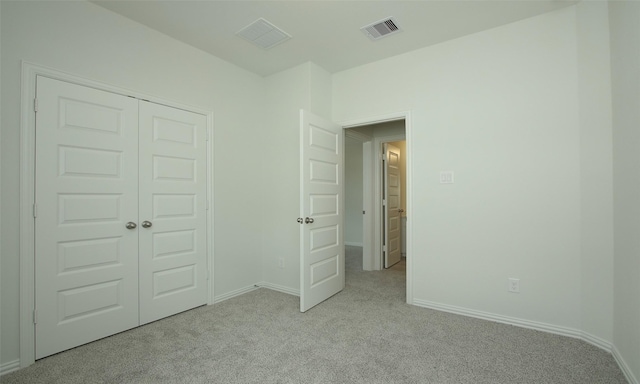 unfurnished bedroom with light carpet and a closet