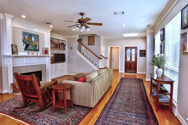 living room featuring a tile fireplace, ceiling fan, and light wood-type flooring