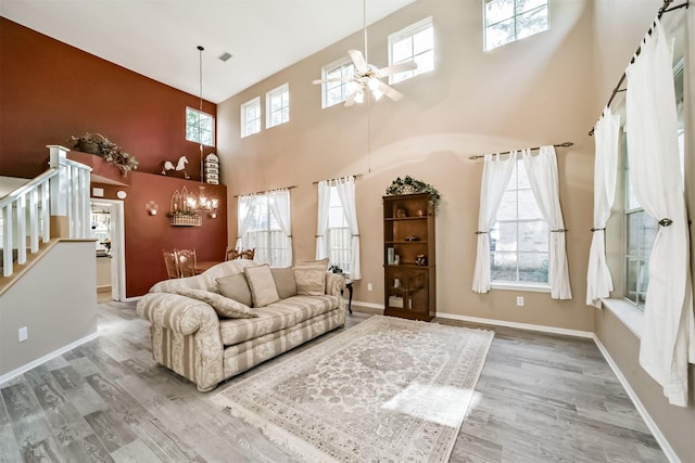 living room featuring wood-type flooring, a towering ceiling, and ceiling fan