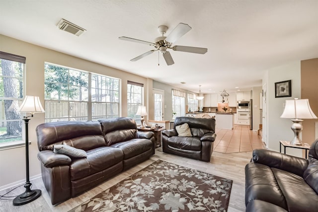 living room featuring ceiling fan, light hardwood / wood-style floors, and a wealth of natural light