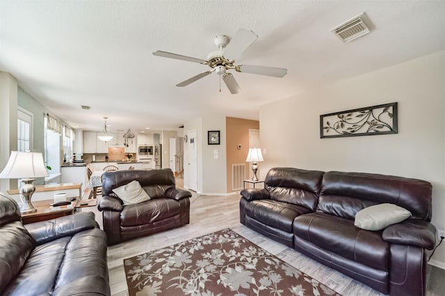 living room with ceiling fan and light hardwood / wood-style floors