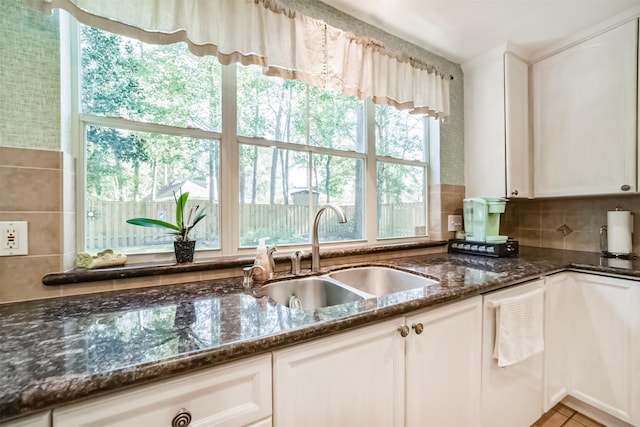 kitchen featuring backsplash, dark stone counters, sink, dishwasher, and white cabinetry