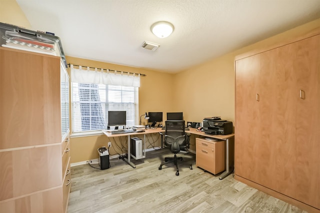 home office with a textured ceiling and light wood-type flooring