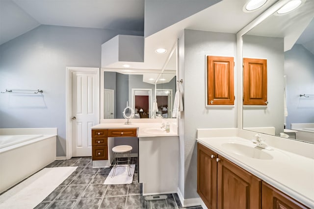 bathroom with tile patterned flooring, vanity, lofted ceiling, and a tub to relax in