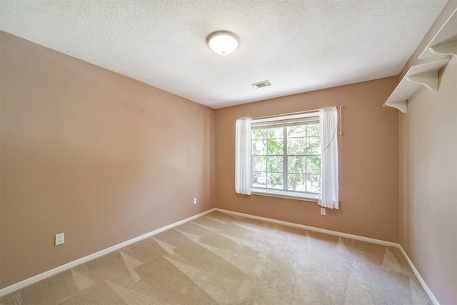 spare room with light colored carpet and a textured ceiling