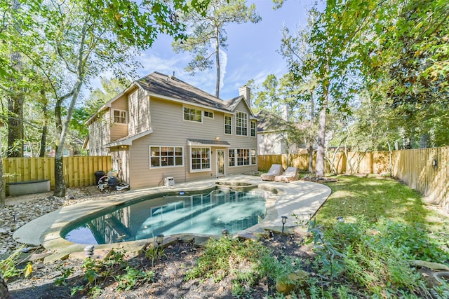 rear view of house with a fenced in pool and a patio area